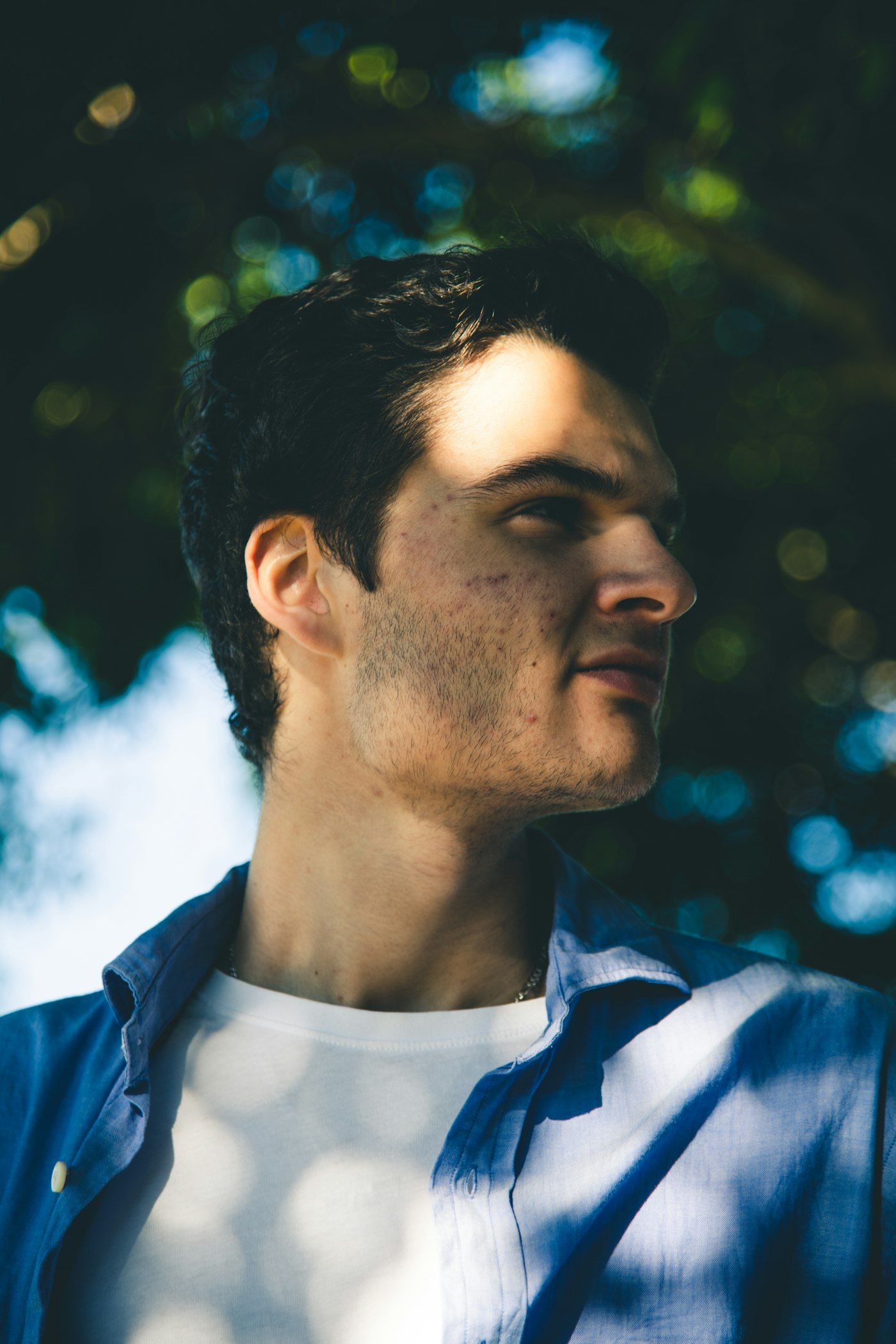 Profile portrait of a man in a blue shirt against a soft, blurred background
